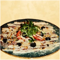 Dungesneden plakjes ossenhaas met rucola, parmezaanse kaas, pijnboompitten olijven en olijfolie