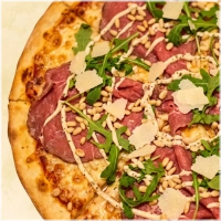 Dungesneden plakjes ossenhaas met rucola, parmezaanse kaas, pijnboompitten olijven en olijfolie
