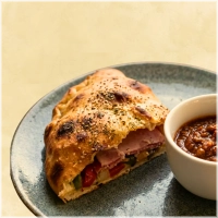 Dubbelgevouwen pizza met ham, salami en gebakken paprika, ui en champignons. en apart bakje bolognese saus