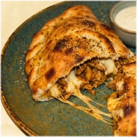 Dubbelgevouwen pizza met shoarmavlees en 2 bakjes knoflooksaus